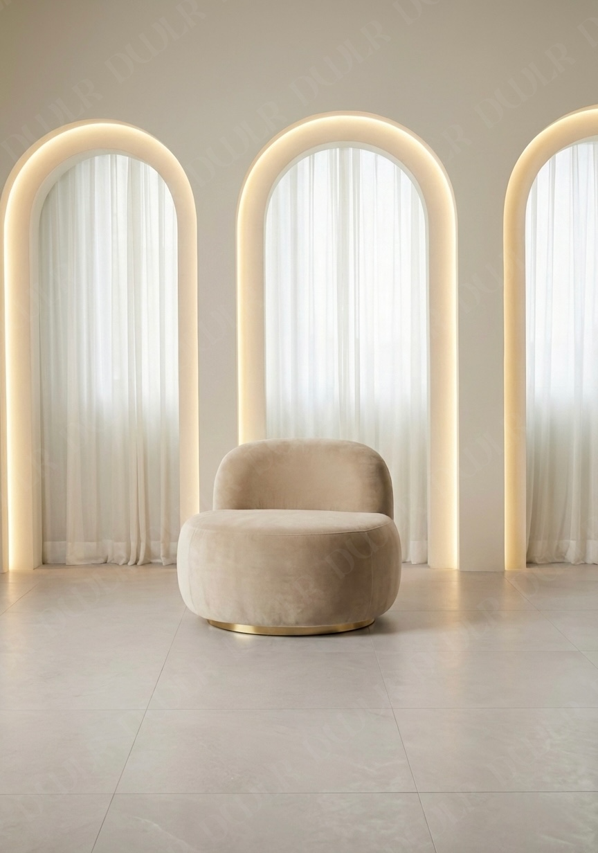 Modern beige armchair in a room with arch-shaped light fixtures and white curtains.