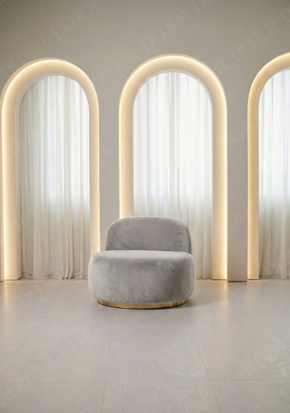 Gray chair in front of three arched mirrors with a neutral background