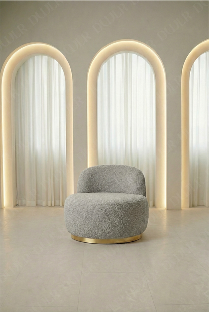 Gray armchair in a room with arch-shaped light fixtures and white curtains.