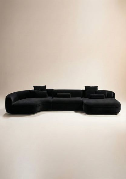Large curved modular sofa in black velvet upholstery with sculptural form and modular layout