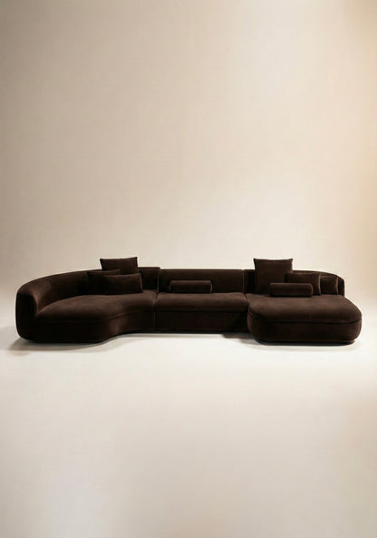 Large curved modular sofa in taupe velvet upholstery with sculptural form and modular layout