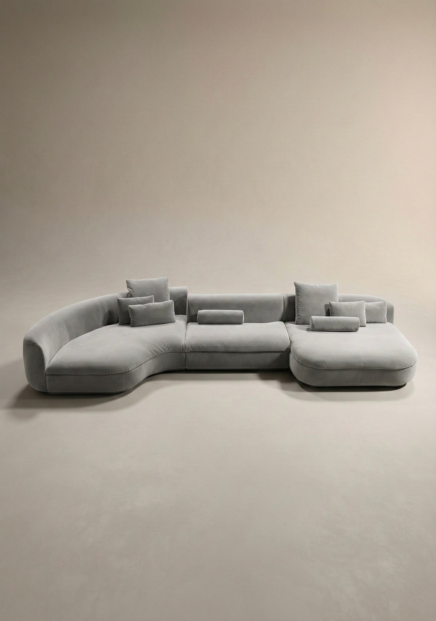 Large curved modular sofa in grey  velvet upholstery with sculptural form and modular layout