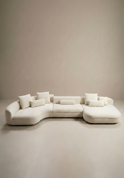 Large curved modular sofa in off white velvet upholstery with sculptural form and modular layout