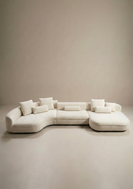 Large curved modular sofa in off white velvet upholstery with sculptural form and modular layout