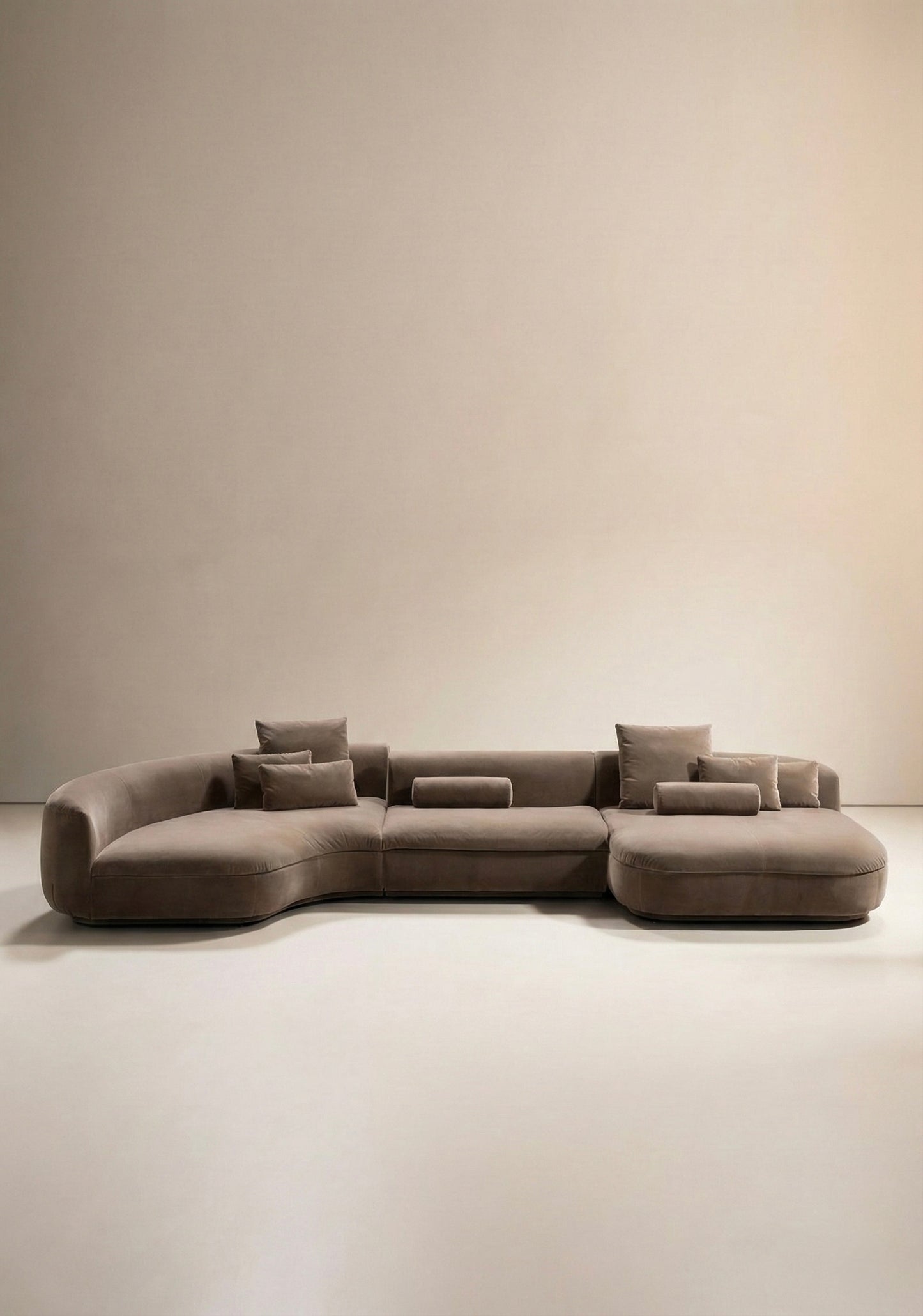 Large curved modular sofa in taupe velvet upholstery with sculptural form and modular layout