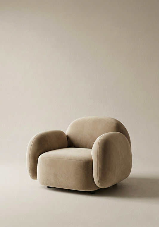 Nimi Armchair in light neutral upholstery with rounded arms and curved silhouette