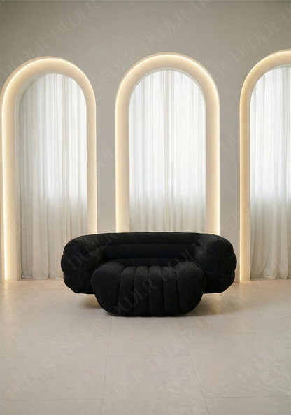 Modern black sofa in a room with arch-shaped light fixtures and white curtains.