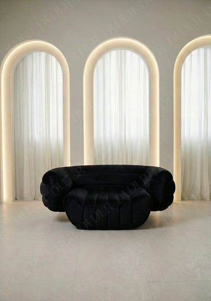 Black sofa in a room with three arched light fixtures and white curtains.
