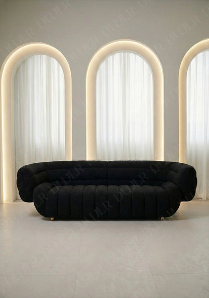 Solara sofa in black boucle upholstery with curved silhouette and channel tufted seat in modern living room.