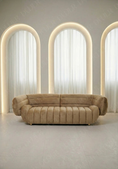 Solara sofa in beige velvet upholstery with curved silhouette and channel tufted seat in modern living room