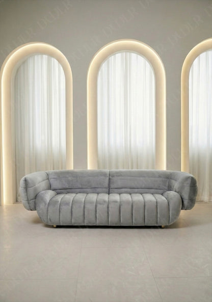 Solara sofa in light grey velvet upholstery with curved silhouette and channel tufted seat in modern living room