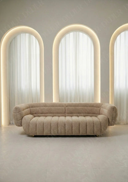 Solara sofa in beige boucle upholstery with curved silhouette and channel tufted seat in modern living room.
