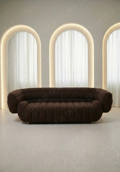 Solara sofa in brown boucle upholstery with curved silhouette and channel tufted seat in modern living room.