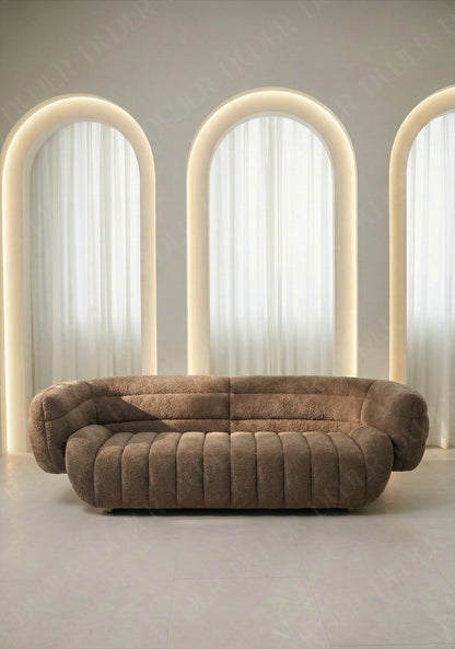 Solara sofa in taupe boucle upholstery with curved silhouette and channel tufted seat in modern living room.