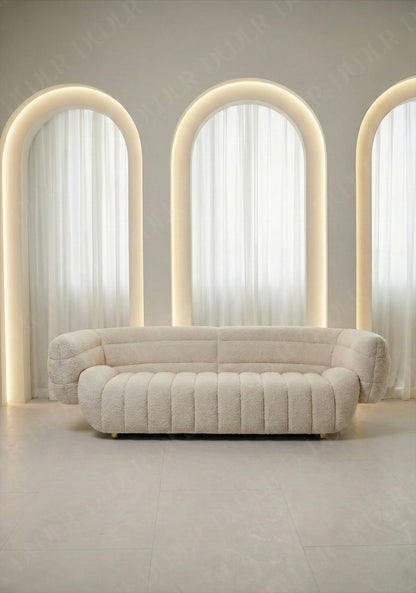Solara sofa in off white taupe boucle upholstery with curved silhouette and channel tufted seat in modern living room.